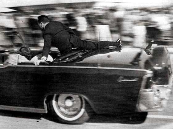 A Secret Service agent leaps onto the presidential limousine.