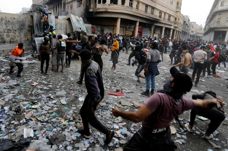 Iraqi demonstrators throw stones towards Iraqi security force.