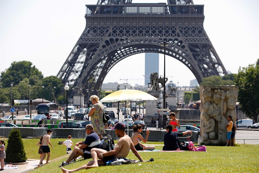 People sunbathe near the Trocadero fountains and the Eiffel tower