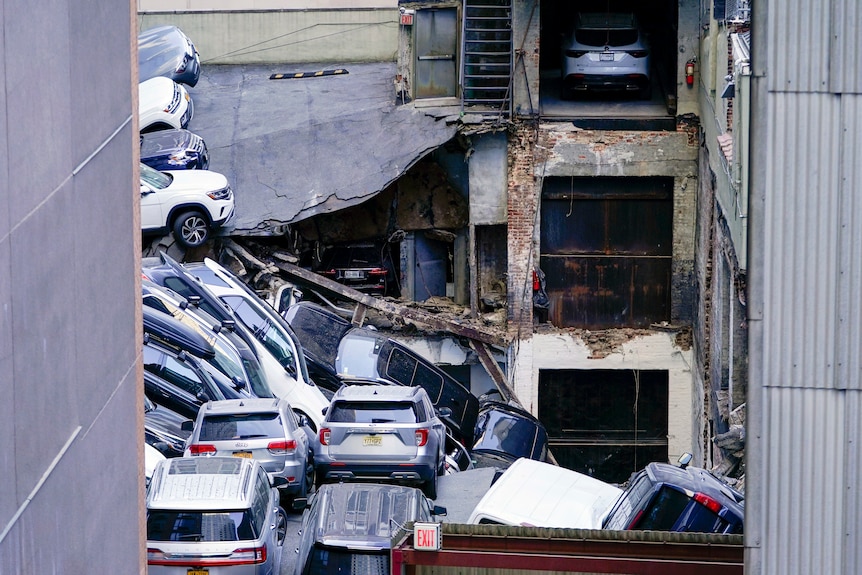 Cars are seen piled on top of each other at the scene of a partial collapse of a parking garage