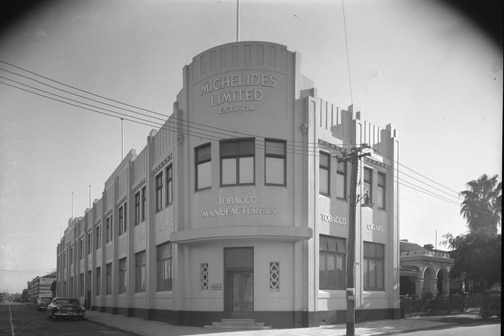 Historic black and white photo of a corner building signed Michelides limited.