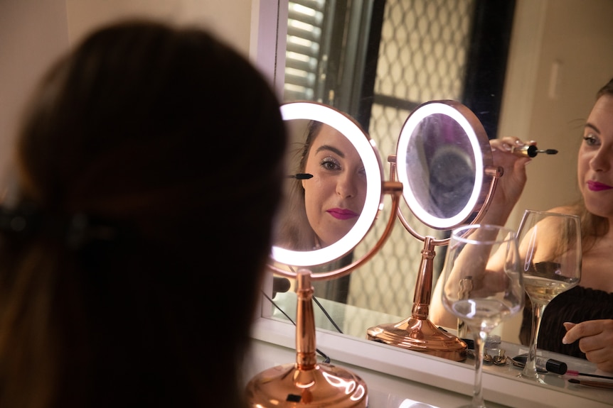 Sophie Morris applying mascara in a magnifying mirror.