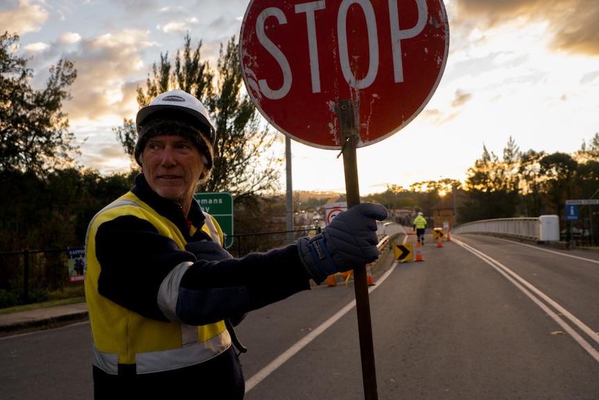 A worker stops traffic on the main street of Cobargo.