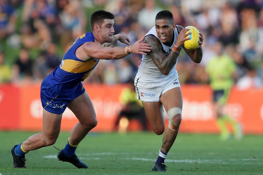 Dockers player Michael Walters gets away from Eagles opponent Elliot Yeo while carrying the ball during a pre-season game.