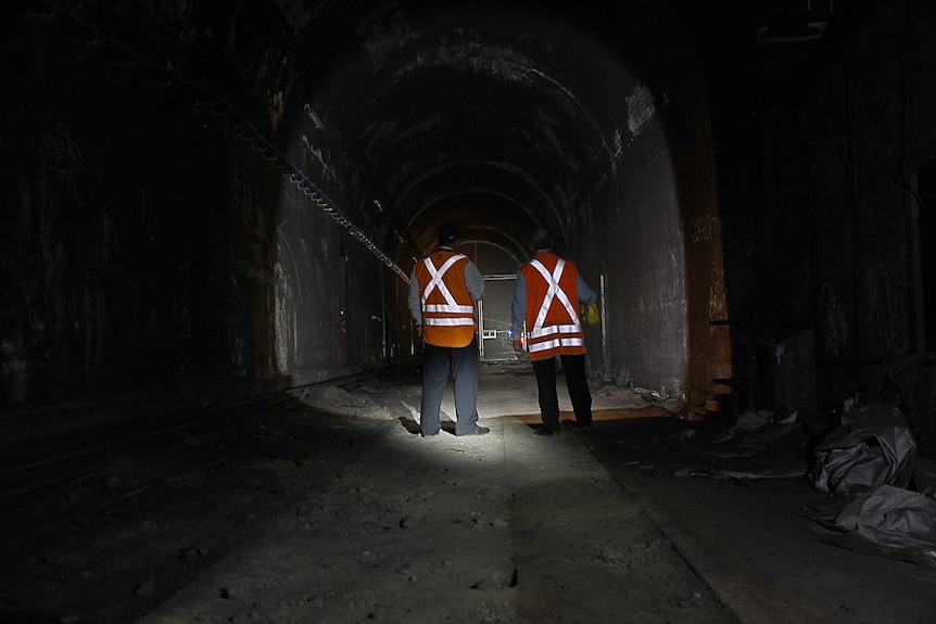 Two men inspect the state of the rail tunnel