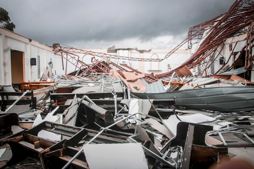 The remains of a damaged structure lies on the ground in a heap of metal.