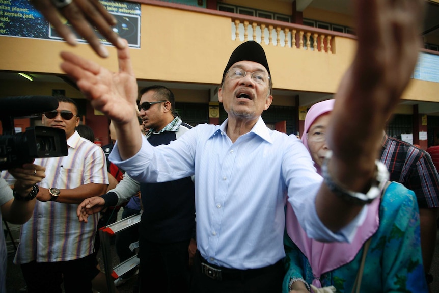 Anwar Ibrahim greets supporters after casting his vote.