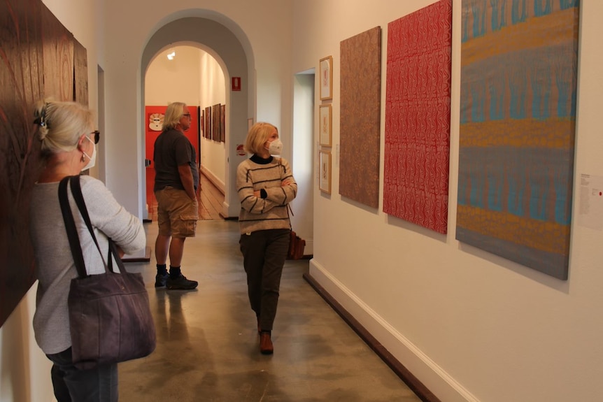 People walk down a corridor looking at artwork
