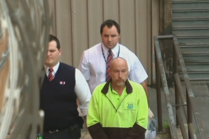 A prisoner under escort by two court officials.