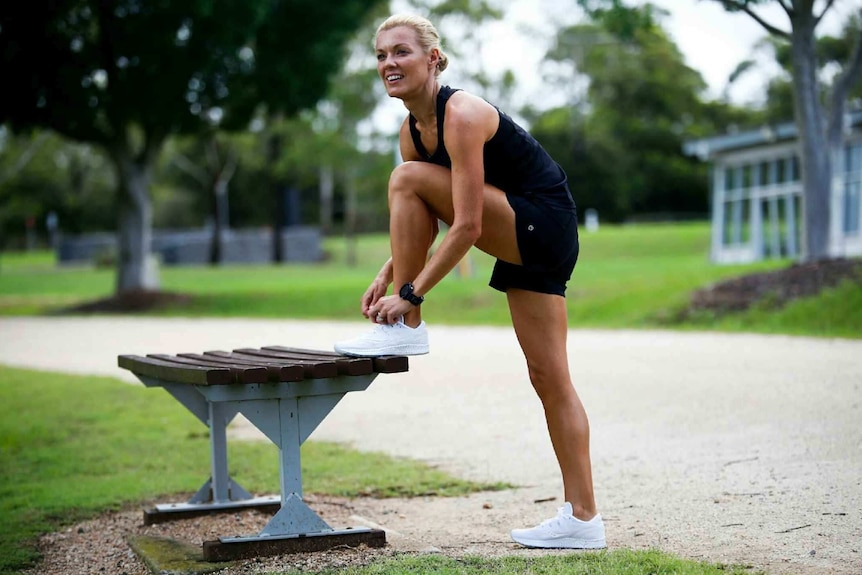 A woman does up her shoelace ready to go for a run in the park.