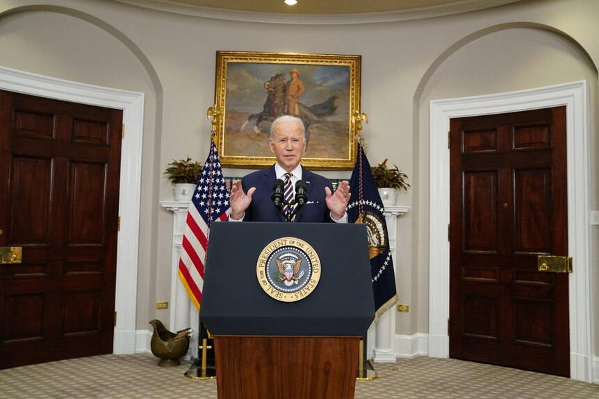 Joe Biden delivering a speech at a lectern in an official building.