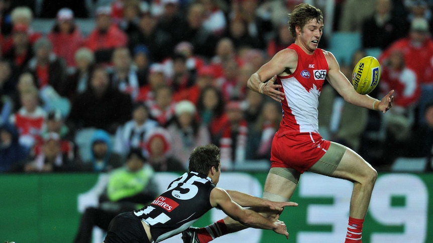 Sydney Swans' Alex Johnson (R) juggles the ball ahead of Jamie Elliott from the Collingwood Magpies.