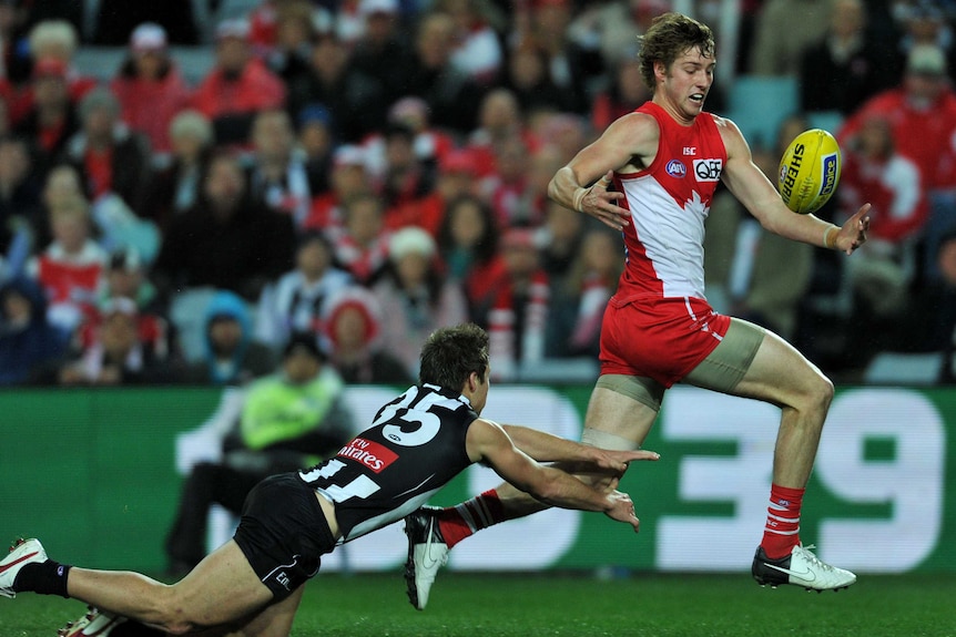 Sydney Swans' Alex Johnson (R) juggles the ball ahead of Jamie Elliott from the Collingwood Magpies.