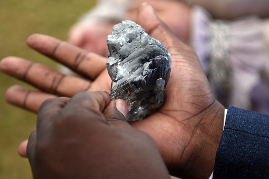 Un diamante del tamaño de una palma se encuentra en la mano de un hombre.