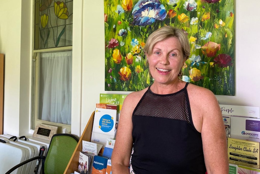 Jeanne Moloney-Nicholls standing in front of a painting of flowers