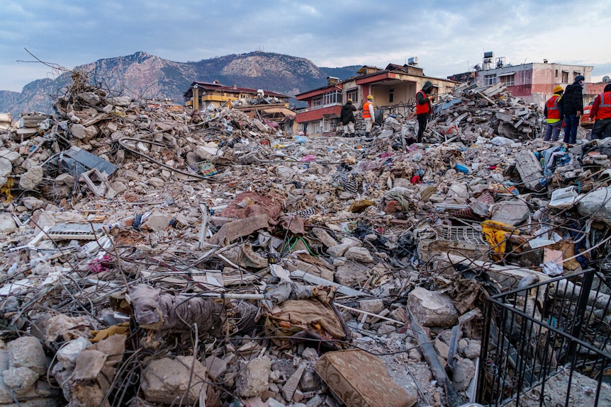Buildings destroyed to rubble with mountains in the background.