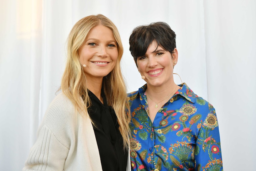 Gwyneth Paltrow and goop chief content officer Elise Loehnen stand together smiling at the In goop Health Summit San Francisco.
