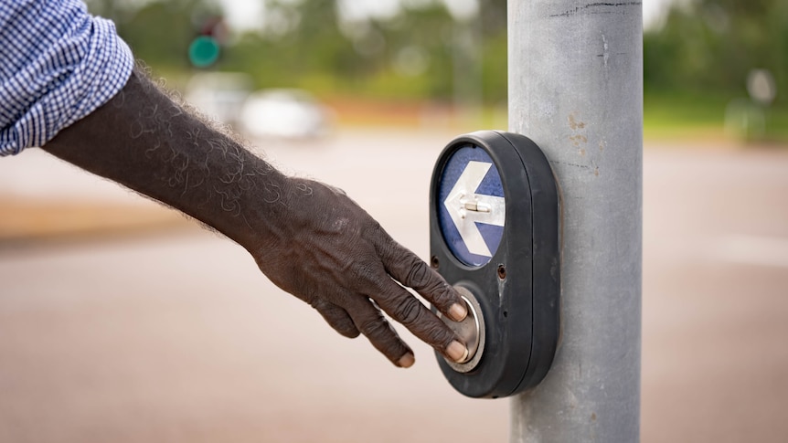 a hand pressing a traffic light button