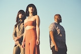 Members of Houston, Texas band Khruangbin stand against the backdrop of a blue sky