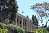 A wide shot of Parliament House in Perth surrounded by trees and blue sky.