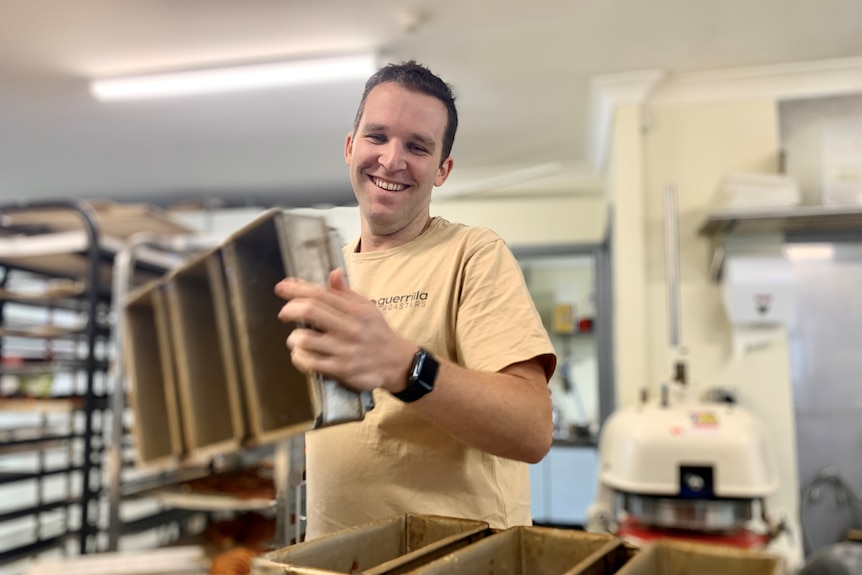 Lagom Bakery co-owner Jon Reeves smiles as he picks up silver bread tins.