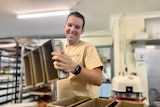 Lagom Bakery co-owner Jon Reeves smiles as he picks up silver bread tins.