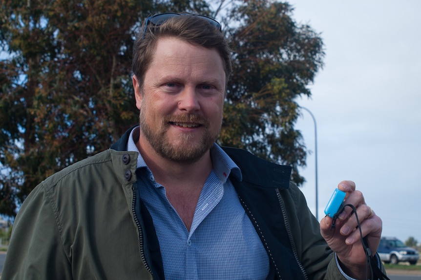 Philip Roetman holds GPS device used in tracking cats.