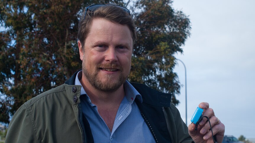 Philip Roetman holds GPS device used in tracking cats.