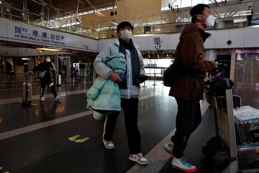 两名戴着口罩的旅客走出首都国际机场航站楼