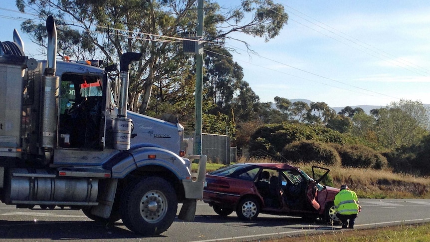 A police officer inspects a car involved in a fatal crash with a truck near Hobart.