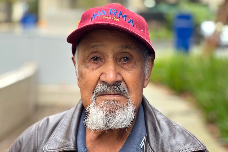 A man wearing a red cap stares directly into the camera.