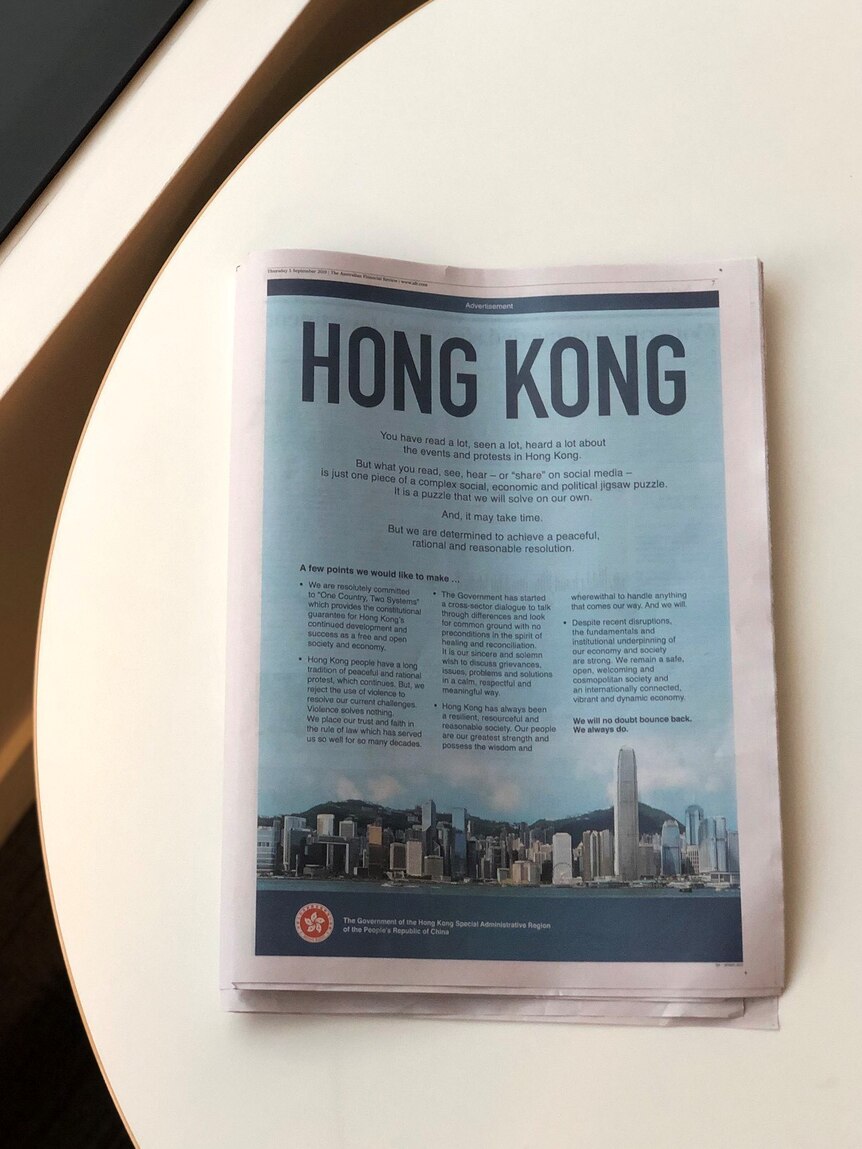 On a white round table, you view a newspaper advertisement with 'Hong Kong' shown in large letters.