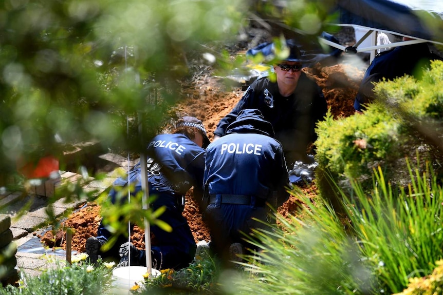 Three people kneeling down digging.