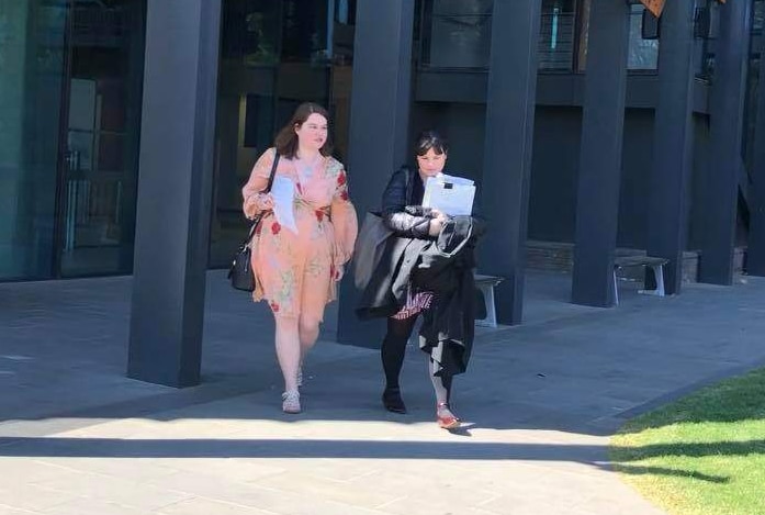 Young woman and lawyer walk out of of a court complex in Victoria.