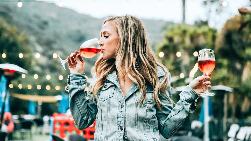 Woman sitting on a table with two glasses of rose wine