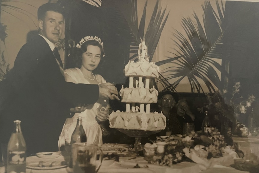 Old wedding photo of man and woman cutting a three-tiered cake.