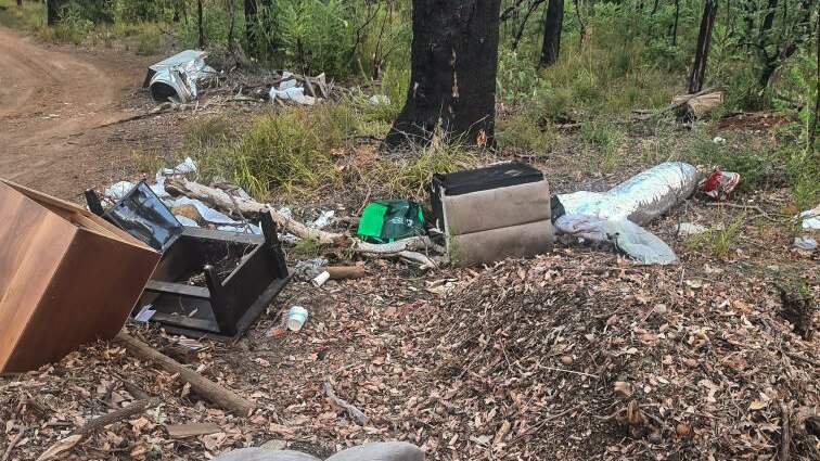 Rubbish strewn around natural bushland, sofa pieces, furniture, clothing
