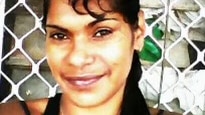 A medium close-up of a smiling woman with black hair and a black singlet