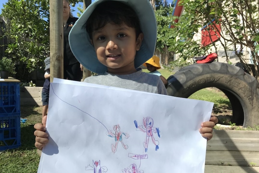 A four-year-old boy at a daycare centre at Mitchelton on Brisbane's northside holds up a drawing.