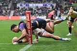 NRL player Xavier Coates grounds the ball for a try, while the rest of his body is airborne