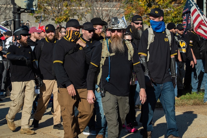 men in black and yellow polo shirts and hats walk outside in a group