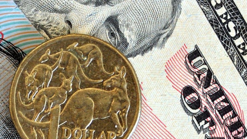 An Australian one-dollar coin, placed on top of US dollars.