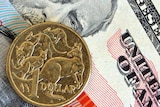 An Australian one-dollar coin, placed on top of US dollars.