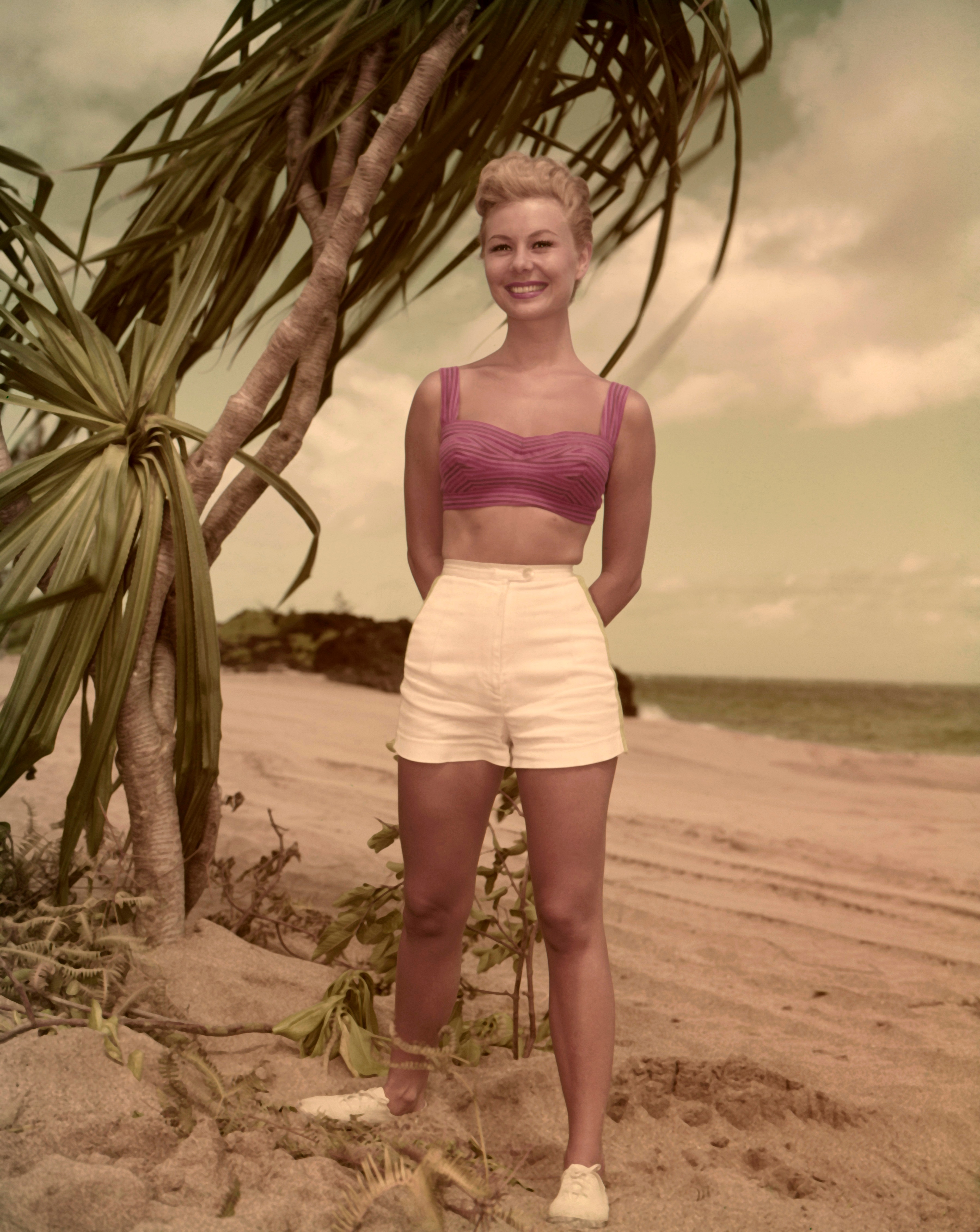 Woman wearing pink bikini and white shorts on the beach 