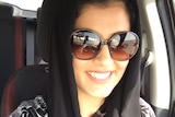 A self-portrait of Loujain Houthlou, who is smiling while driving and wearing sunglasses and a head scarf.