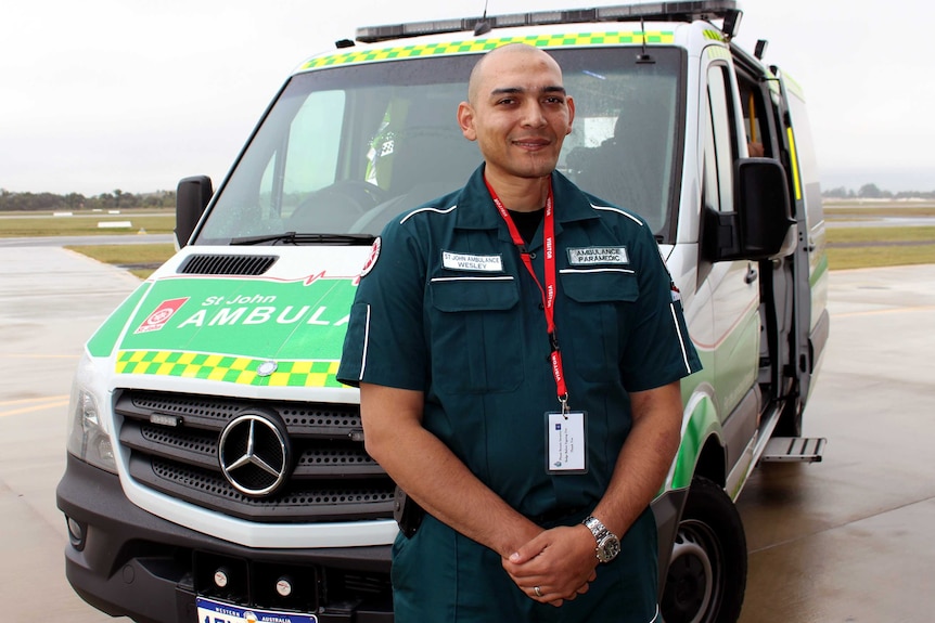 Paramedic Wesley Ackerman standing in front of an ambulance.