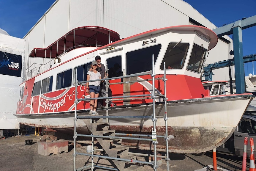 Man, woman standing next to ferry on hardstand