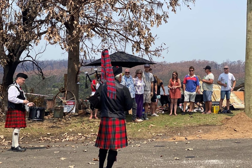 A man playing bagpipes in front of people