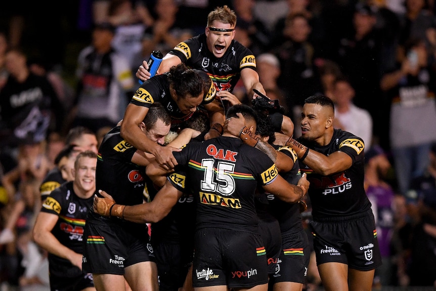 Rugby league players jumping on one another in celebration after winning a match.