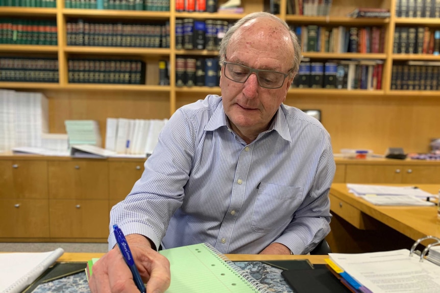 Tim Tobin at a desk with a pen looks at papers.